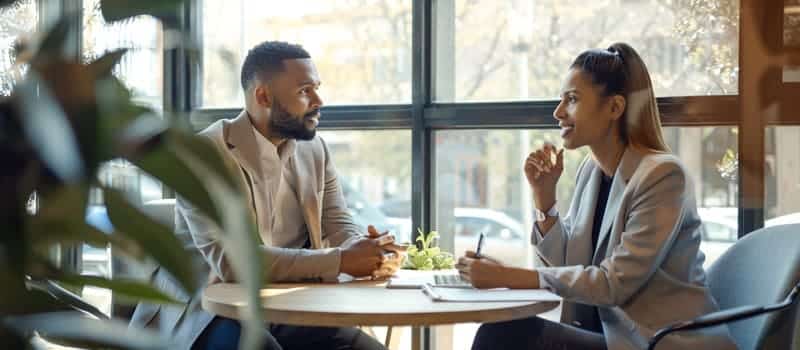 Coach et client échangeant autour d'une table lors d'une séance de coaching professionnel